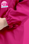 Close-up of an arm wearing a bright pink BARBARA PINK WINDBREAKER from looselyboho with an elasticated cuff. The lightweight, water-resistant fabric appears glossy. In the upper left corner, there is a logo with the words "Barbara Pink" and "Limited Edition." The background matches the jacket's vibrant shade of pink.